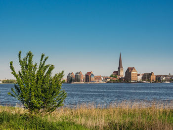 Sea by cityscape against clear sky