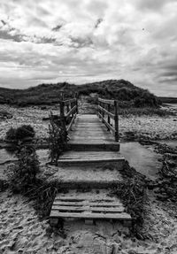 Staircase leading towards shore against sky