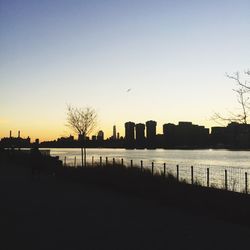 Silhouette cityscape against clear sky during sunset