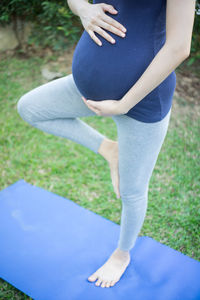 Low section of woman touching grass