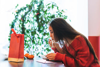 Beautiful smiling young asian woman in red clothes eating asian food in chinese  restaurant