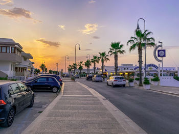 Cars on road against sky during sunset