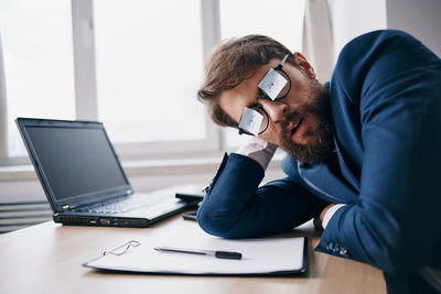 Young businessman with paper on eyeglasses at office