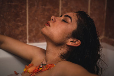 Young woman with flower in bathtub