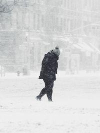 Rear view of man walking on snow field