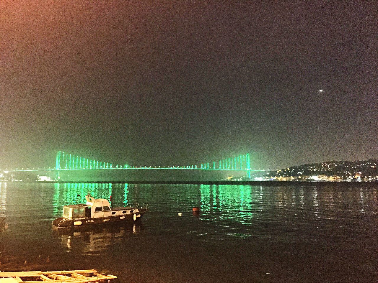 ILLUMINATED PIER OVER SEA AGAINST SKY AT NIGHT