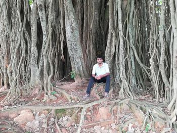 Man sitting on tree trunk in forest