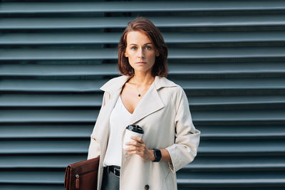 Young woman standing against wall