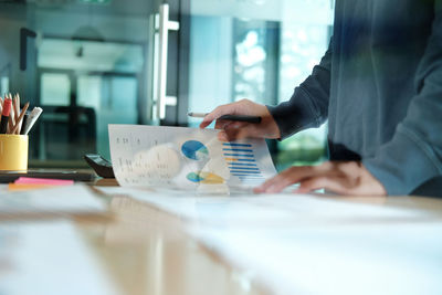 Midsection of businessman analyzing data at table in office