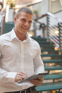 Portrait of a smiling young man holding camera