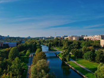 High angle view of river amidst buildings against blue sky