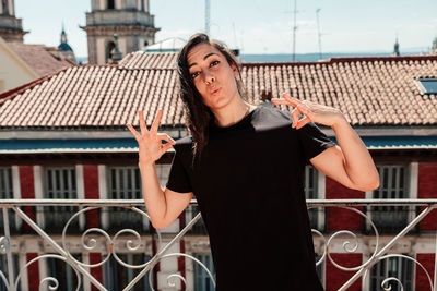 Portrait of woman standing by railing against buildings