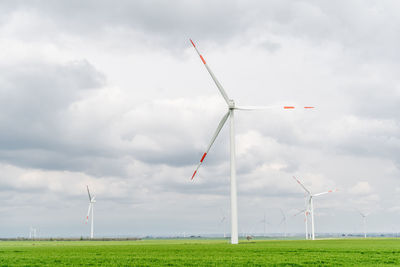 Windmills on field against sky