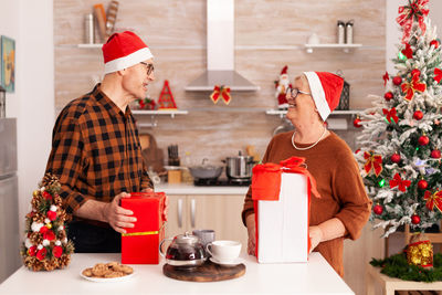 Midsection of man with christmas tree at home