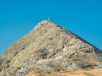 Low angle view of people on rock against sky