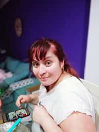 Portrait of smiling mid adult woman using smart phone on table at home