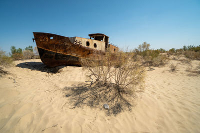 Abandoned boat on beach against sky