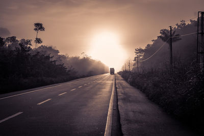 Road amidst trees against sky during sunset