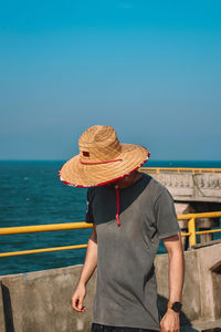 Rear view of man standing by sea against clear sky
