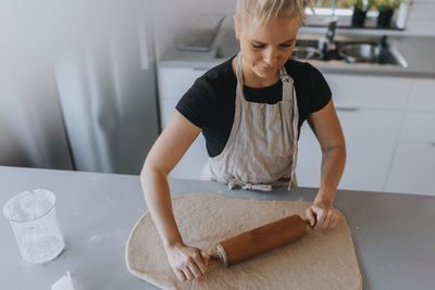 High angle view of woman rolling dough with rolling pin