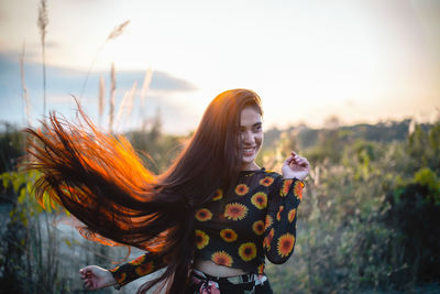 Smiling woman standing against sky during sunset