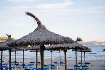 Lounge chairs and parasol on beach against sky