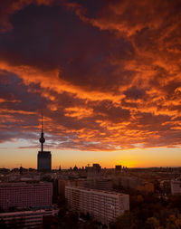 Silhouette buildings against cloudy sky during sunset