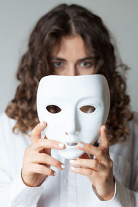 Portrait of woman holding mask over white background