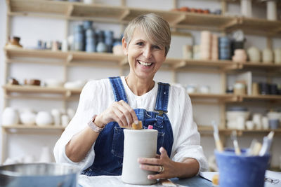 Portrait of smiling mature woman learning pottery in art studio