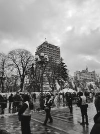 People at town square against cloudy sky