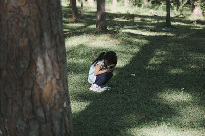 Cute girl crouching on grass at park