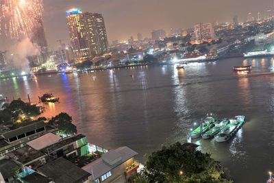 Aerial view of swimming pool by buildings in city at night