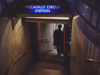 Rear view of man moving down on steps to subway station