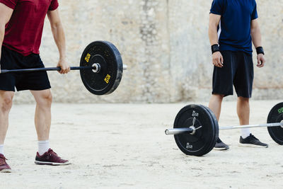 Two weightlifters lifting weights in an urban environment.