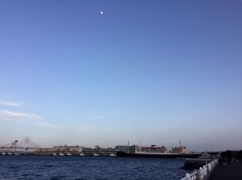 View of city at waterfront against blue sky