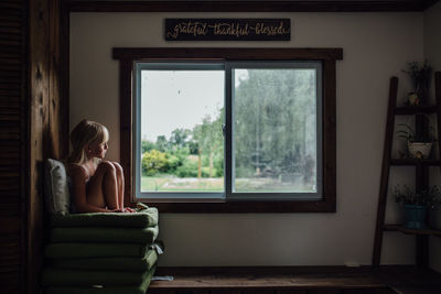 Girl sitting on chair by window at home