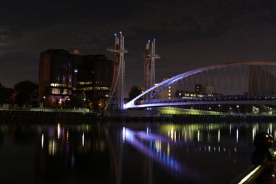 Illuminated bridge over river at night