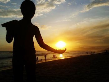 Silhouette woman standing on beach against sky during sunset