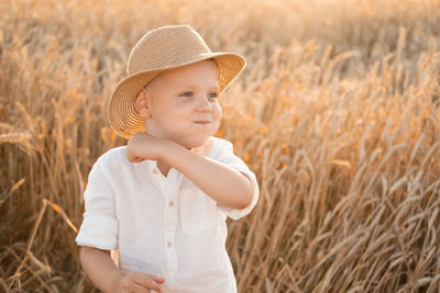 Portrait of young woman wearing hat standing on field