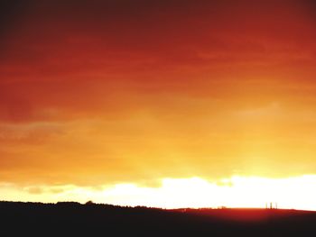 Scenic view of silhouette landscape against orange sky