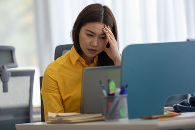 Depressed businesswoman wearing mask sitting at office