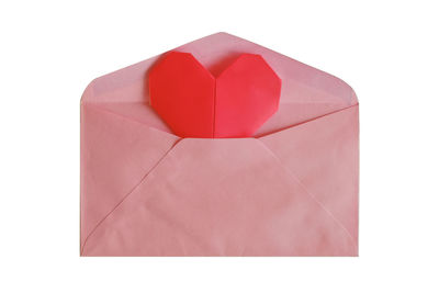 Close-up of red heart shape in envelope against white background