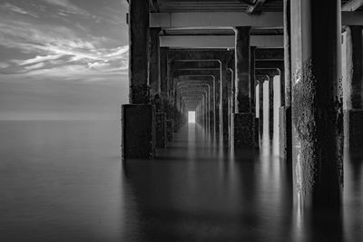 Reflection of bridge in sea against sky