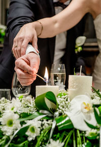 Midsection of newlywed couple lighting candles at wedding ceremony