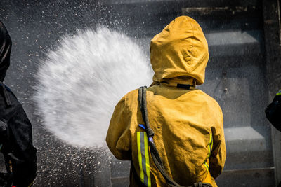 Rear view of person spraying water on wall