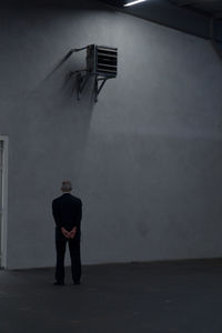 Rear view of man standing against wall