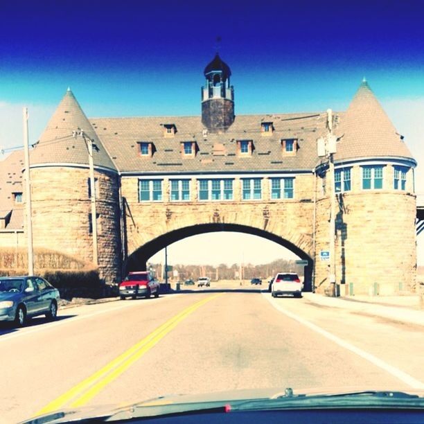 architecture, building exterior, built structure, blue, transportation, car, road, street, church, land vehicle, mode of transport, city, incidental people, clear sky, religion, place of worship, road marking, the way forward, sunlight