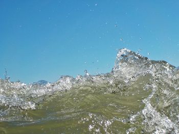 Water splashing in sea against clear blue sky