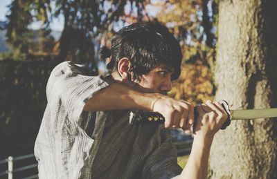 Portrait of young man standing against tree