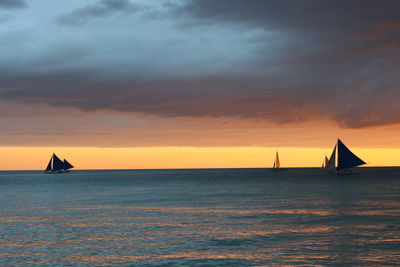 Sailboat sailing on sea against sky during sunset